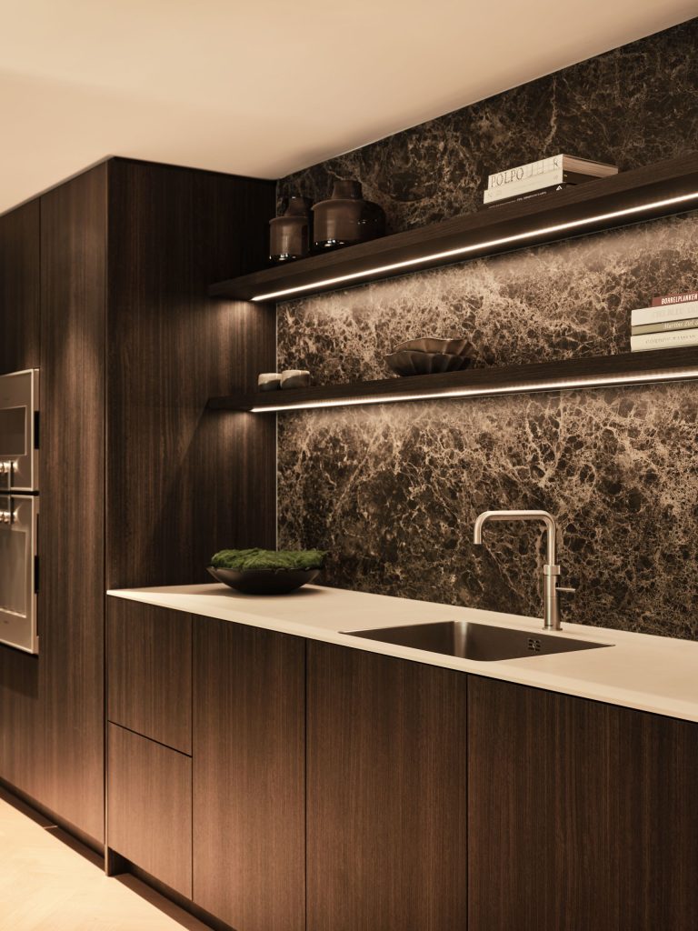 Maatwerk keuken met Decolegno houtafwerking, natuursteen achterwand, geïntegreerde verlichting en Gaggenau apparatuur in een woonboerderij in Roden, ontworpen door DUIN Interior en gerealiseerd door A&F Interieurbouw.
