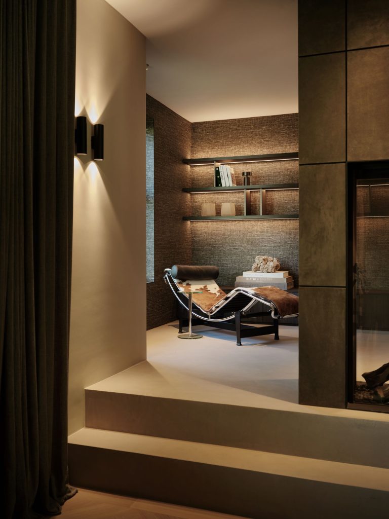 Maatwerk roomdivider met geïntegreerde haard, wandbekleding en verlichte wandplanken in een woonboerderij in Roden, ontworpen door DUIN Interior en gerealiseerd door A&F Interieurbouw.
