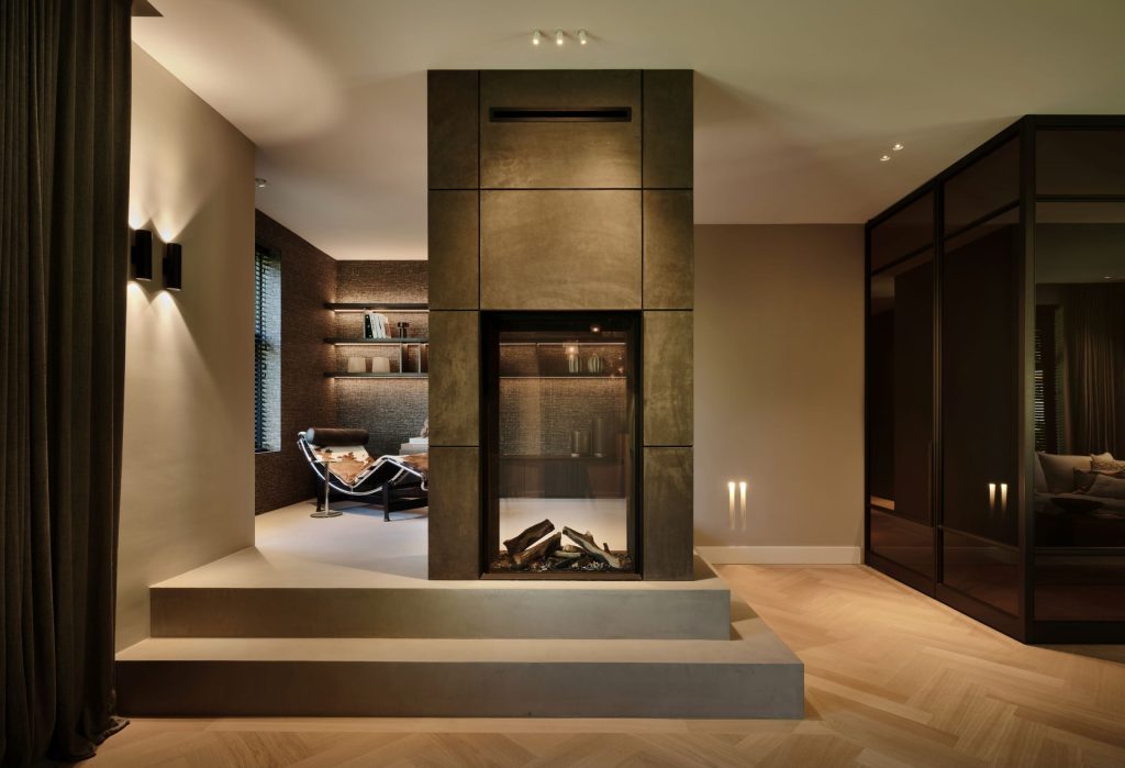 Maatwerk roomdivider met geïntegreerde haard, luxe wandafwerking en maatwerk kastenwand in een woonboerderij in Roden, ontworpen door DUIN Interior en gerealiseerd door A&F Interieurbouw.