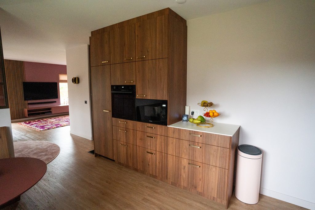Maatwerk kastenwand met geïntegreerde keukenapparatuur, opbergruimte en warme houtafwerking in een woonhuis in Winschoten, ontworpen door Studio Vogt en gerealiseerd door A&F Interieurbouw.