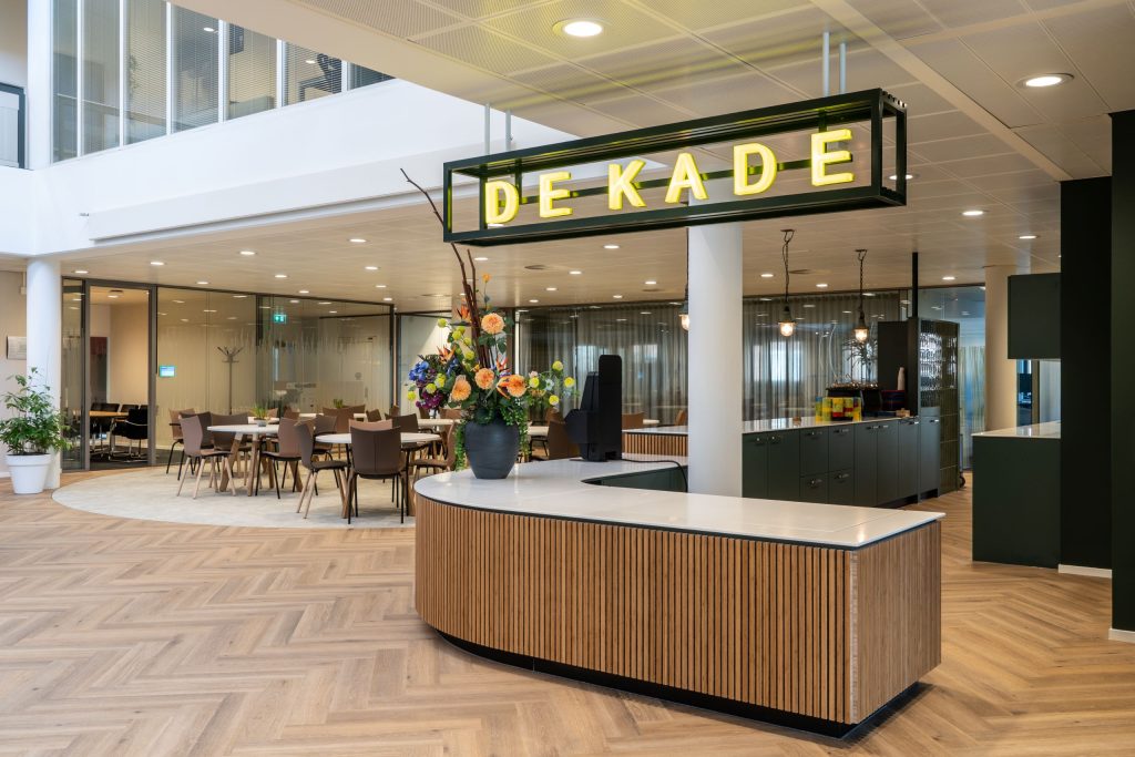 Maatwerk ontvangstbalie met geïntegreerd buffet, HIMACS blad en bamboe lattenfront bij De Zijlen locatie De Kade in Leek, gerealiseerd door A&F Interieurbouw.