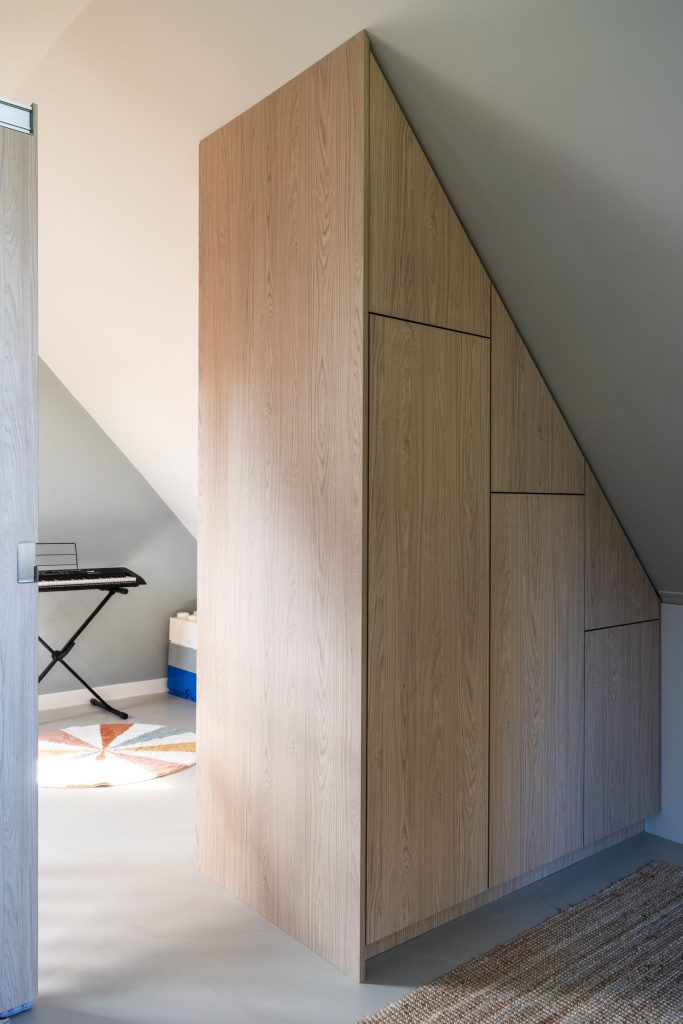 Maatwerk houten kastenwand onder schuin dak op zolder in woonhuis in Haren, Groningen