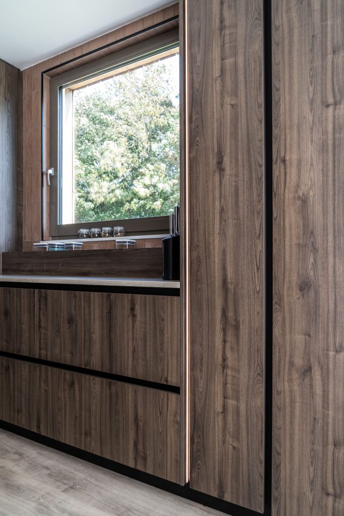 Houten maatwerk kastenwand met geïntegreerde ledverlichting in keuken in Meerstad, Groningen
