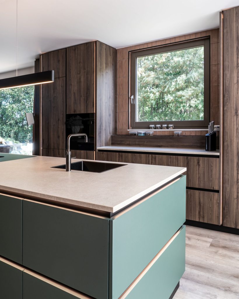 Maatwerk keuken met groen kookeiland, spoelbak en houten kastenwand in Meerstad, Groningen