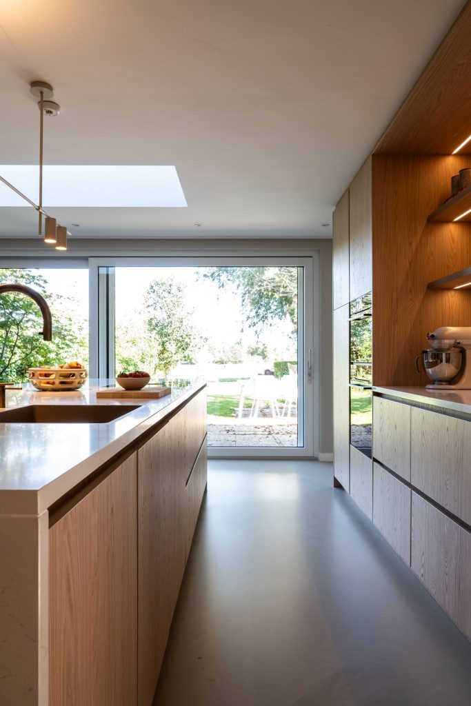 Maatwerk keuken met kookeiland en verlichte nis in Haren Groningen door A&F Interieurbouw naar ontwerp van Studio Skiss